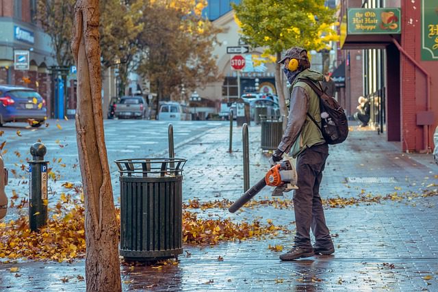 Man using blower to blow leaves off sidewalk